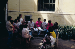 Figura 8- Foto das tradicionais reuniões com os residentes para discutir os casos dos pacientes internados no pátio central do Serviço de Pediatria, no início da década de 1990. Estou sentado no banco de pedra ladeado à esquerda por Dr. Jairo Cesar dos Reis e à minha direita Dr. Carlos Alberto Garcia Oliva.